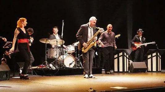 Groupe musical sur scène, autour d'un saxophoniste, se produisant lors d'une soirée associative